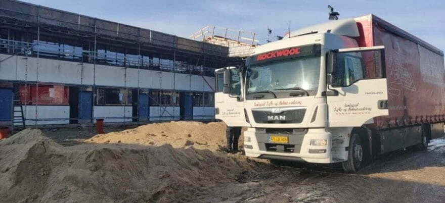 Lastbil foran byggeplads med sandbunke