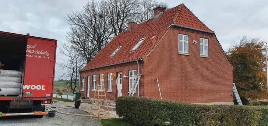 Isoleringsbil ved rødt murstenshus